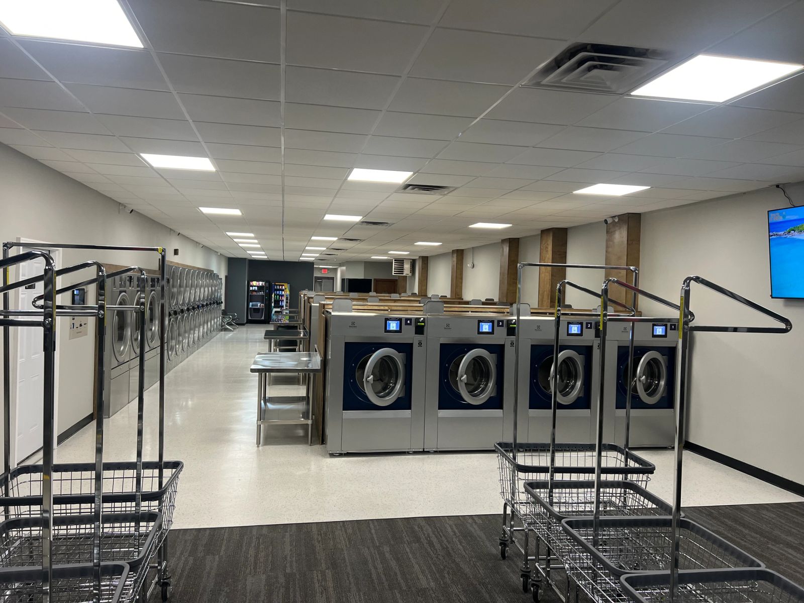 Inside Clean Sheets Laundromat — a bright row of navy Electrolux washers and chrome carts